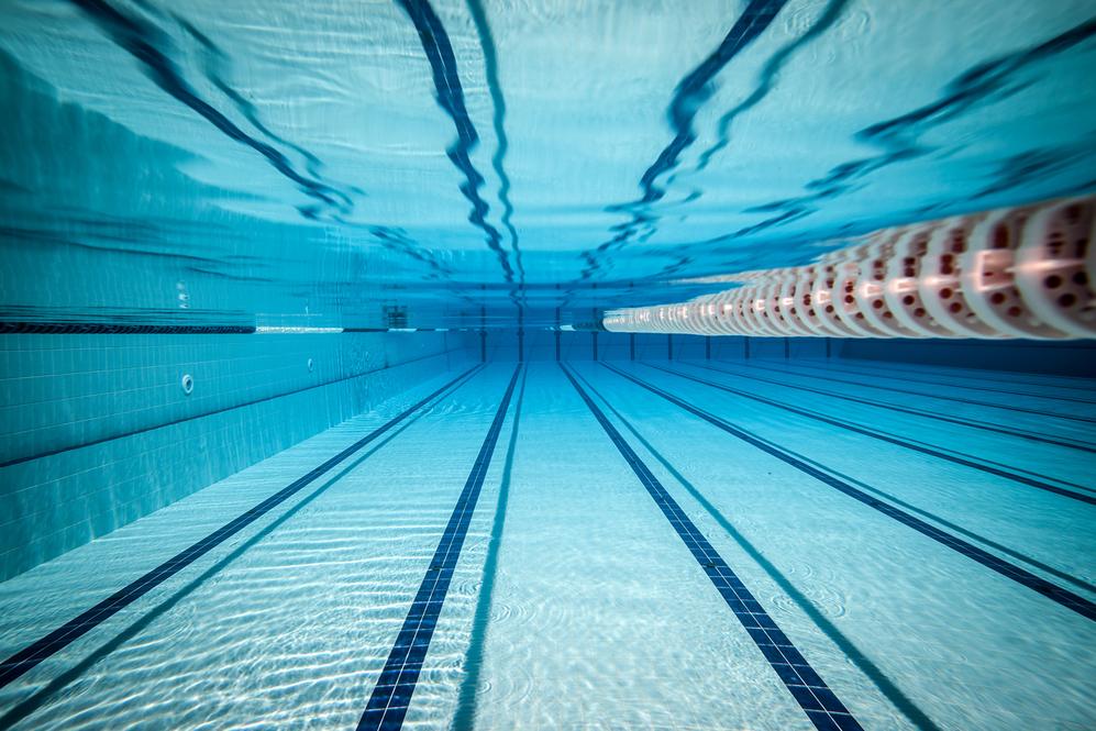 Unterwasseransicht eines Schwimmbeckens mit klaren, blauen Wasser und markierten Bahnen.